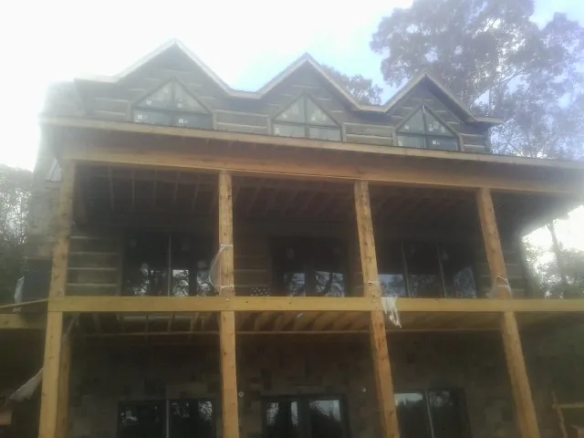 Dormers and porch framing on a large log home under construction — Roof Coating work by our crew in Loretto